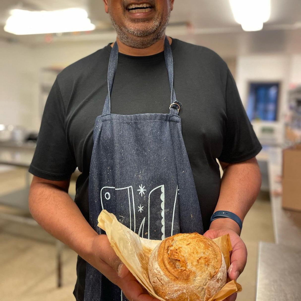sourdough student in apron holding bread he made