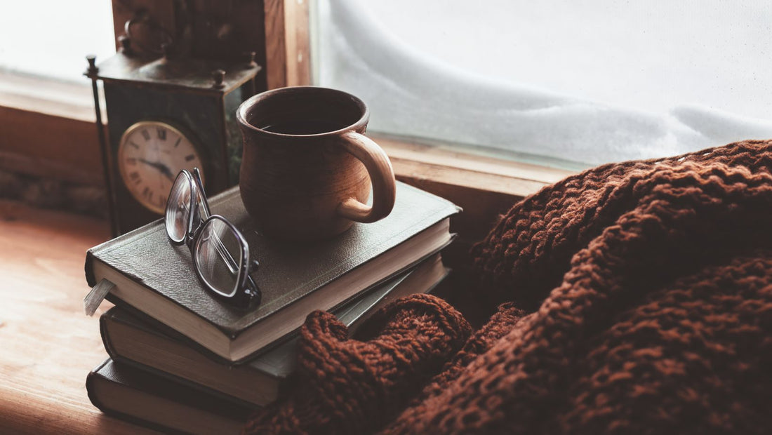 Book, cup of tea, books on a wooden window sill in winter