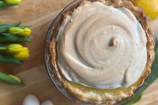 lemon meringue pie with yellow tulips and fresh eggs on a wooden cutting board