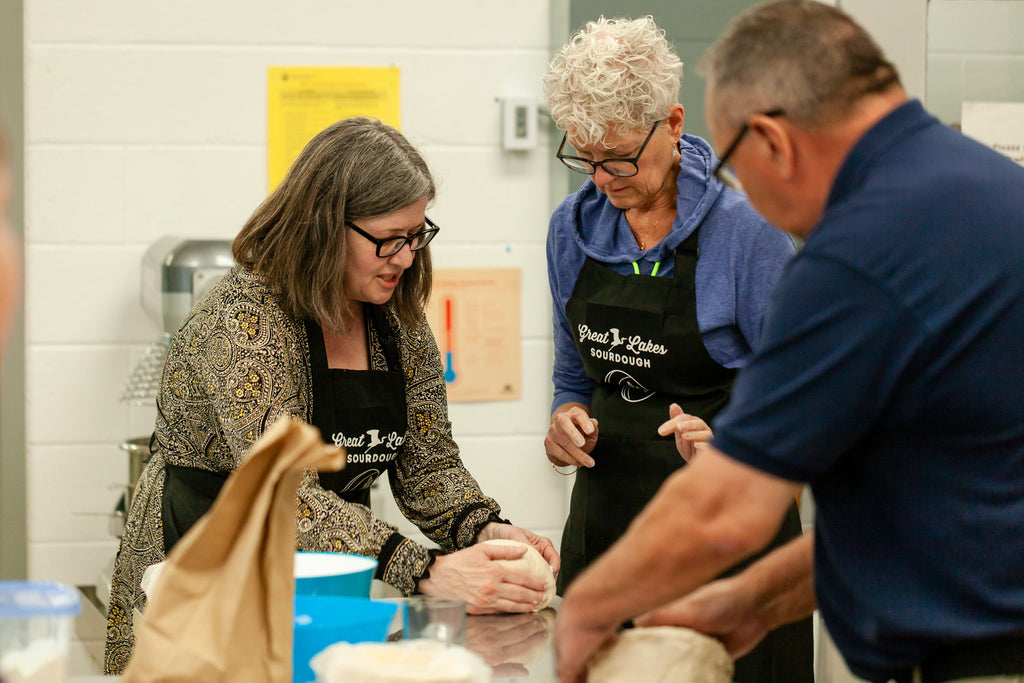 couple learning how to shape bread from teacher in sourdough class 