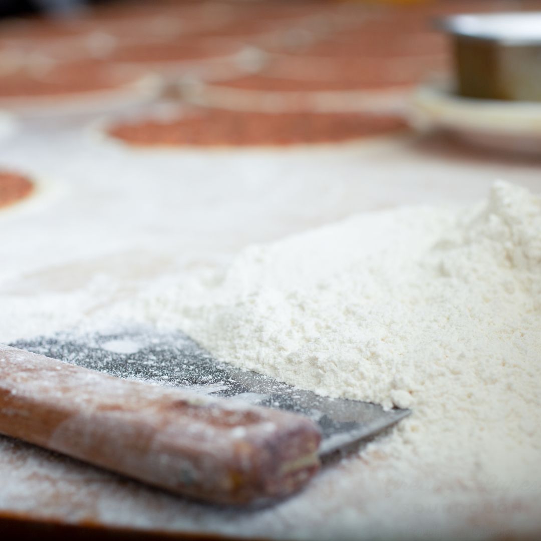 bench scraper on wooden table with flour
