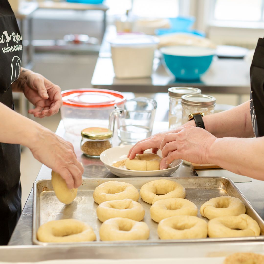 two people adding seeds to bagels