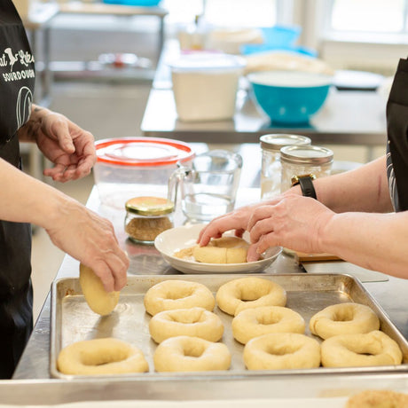 two people adding seeds to bagels
