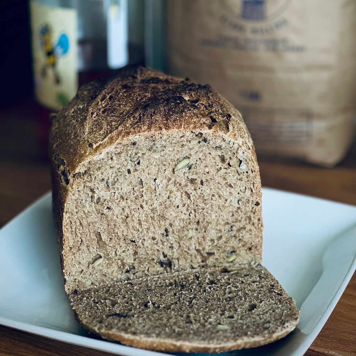 Loaf of red fife sourdough on a white plate with a bag of flour in the background