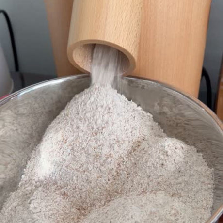 Wooden flour mill milling flour into a metal bowl
